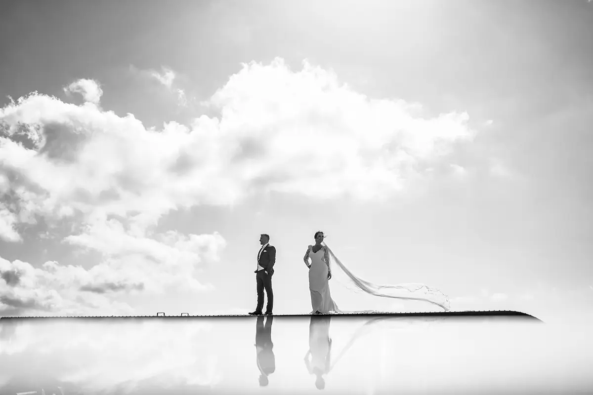 Pareja de novios reflejada sobre una lámina de agua, en blanco y negro
